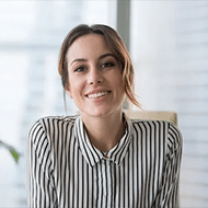 Ai Automation Solutions For Customer Engagement - Desku A smiling woman in a striped shirt sitting at a desk, using ai customer service software.
