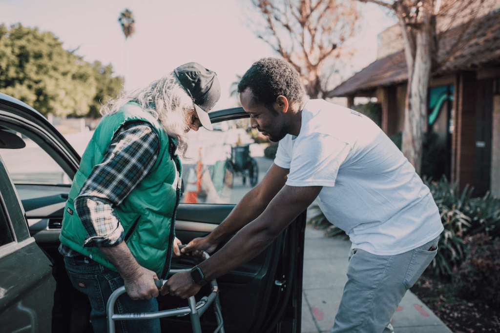 12 Customer Service Phrases To Strengthen Client Relationships - Desku Assisting a man with mobility challenges into a vehicle.